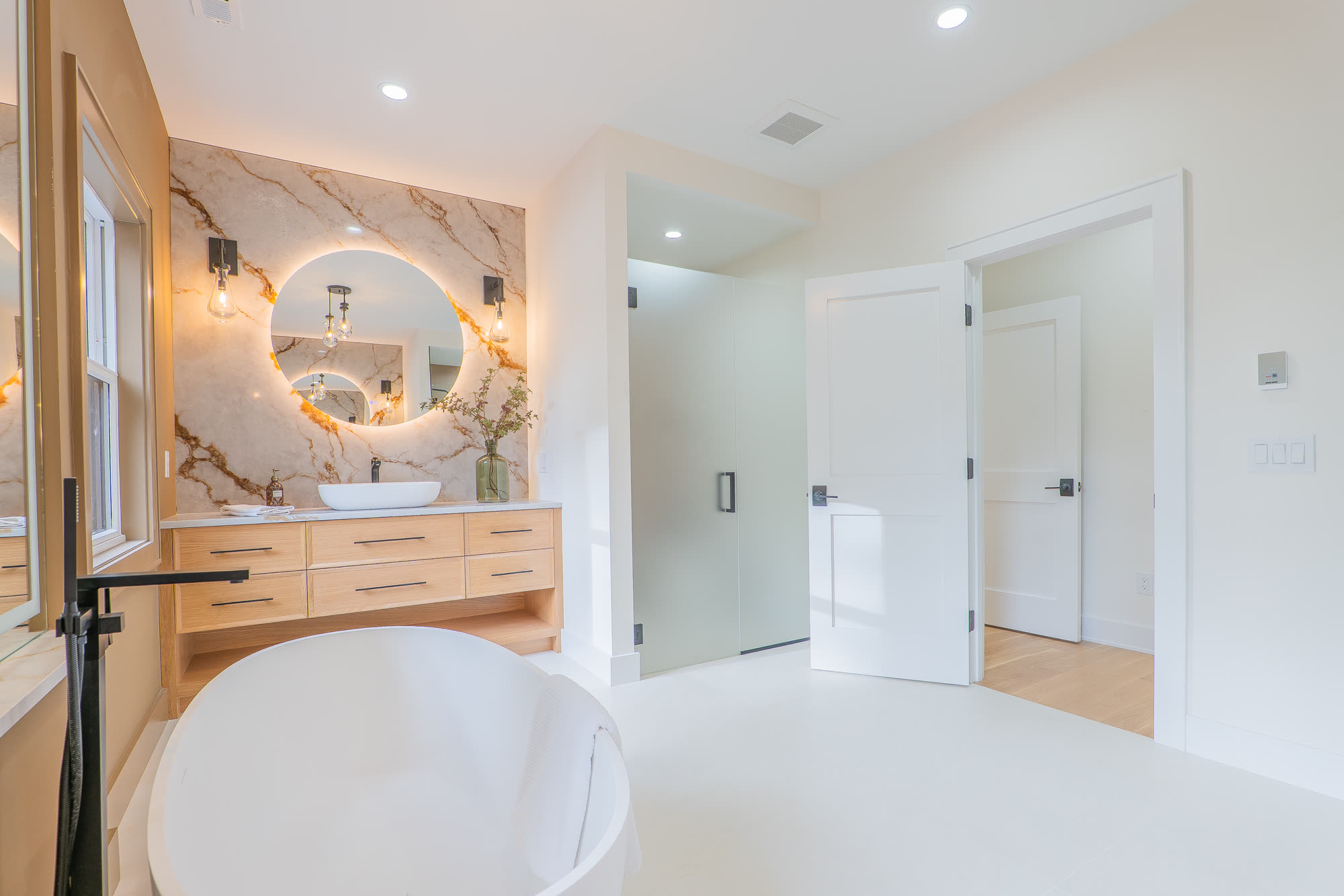 Primary bath vanity with backlit round mirror