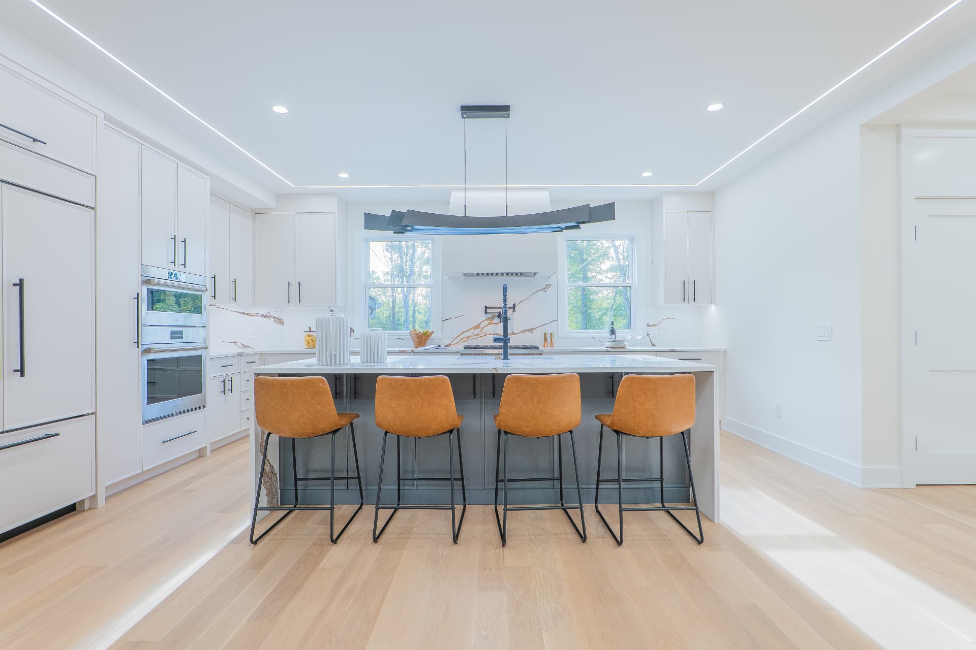 Modern white kitchen with waterfall island and four counter stools
