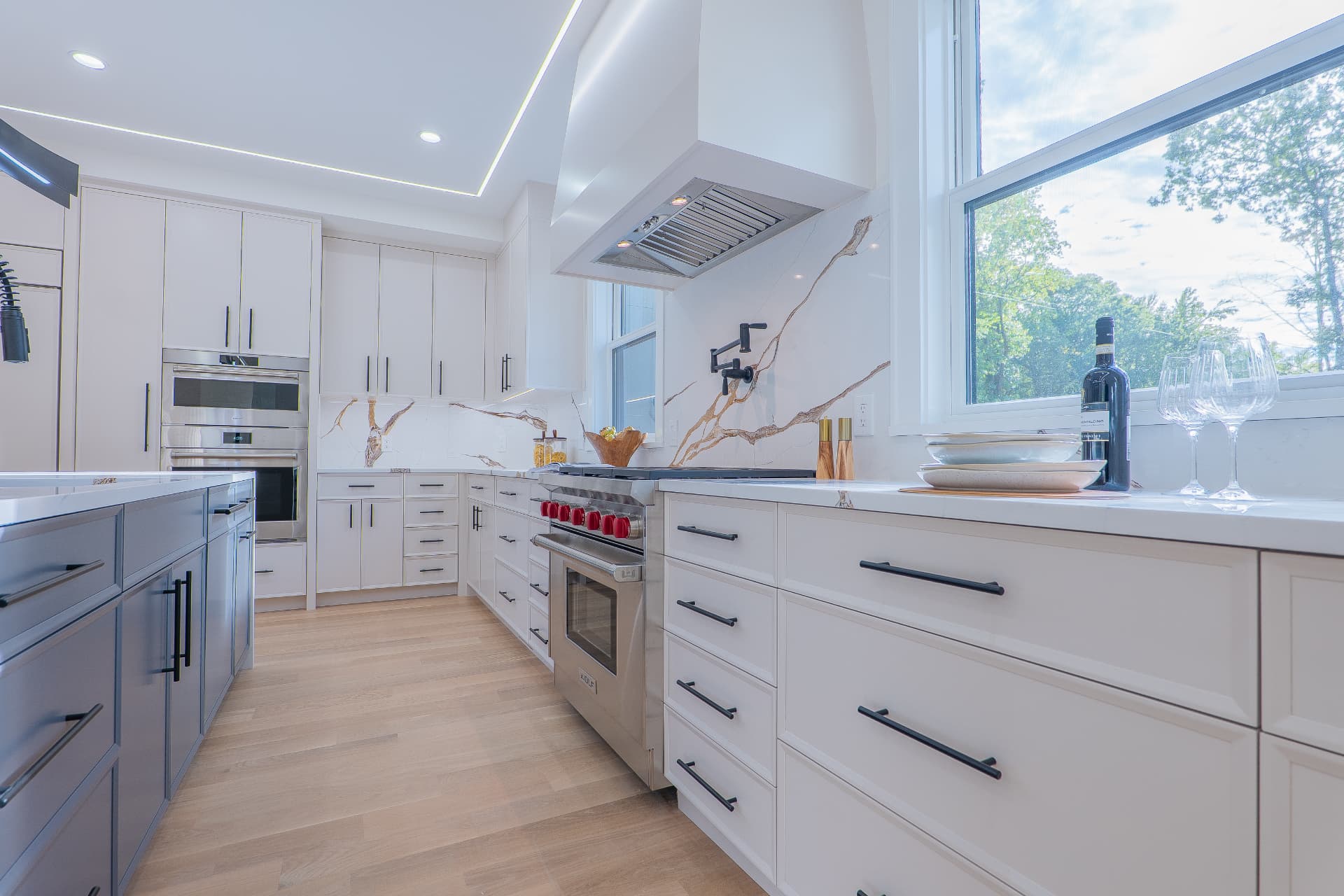 Kitchen with custom cabinetry, quartz counters and professional range hood beside a picture window