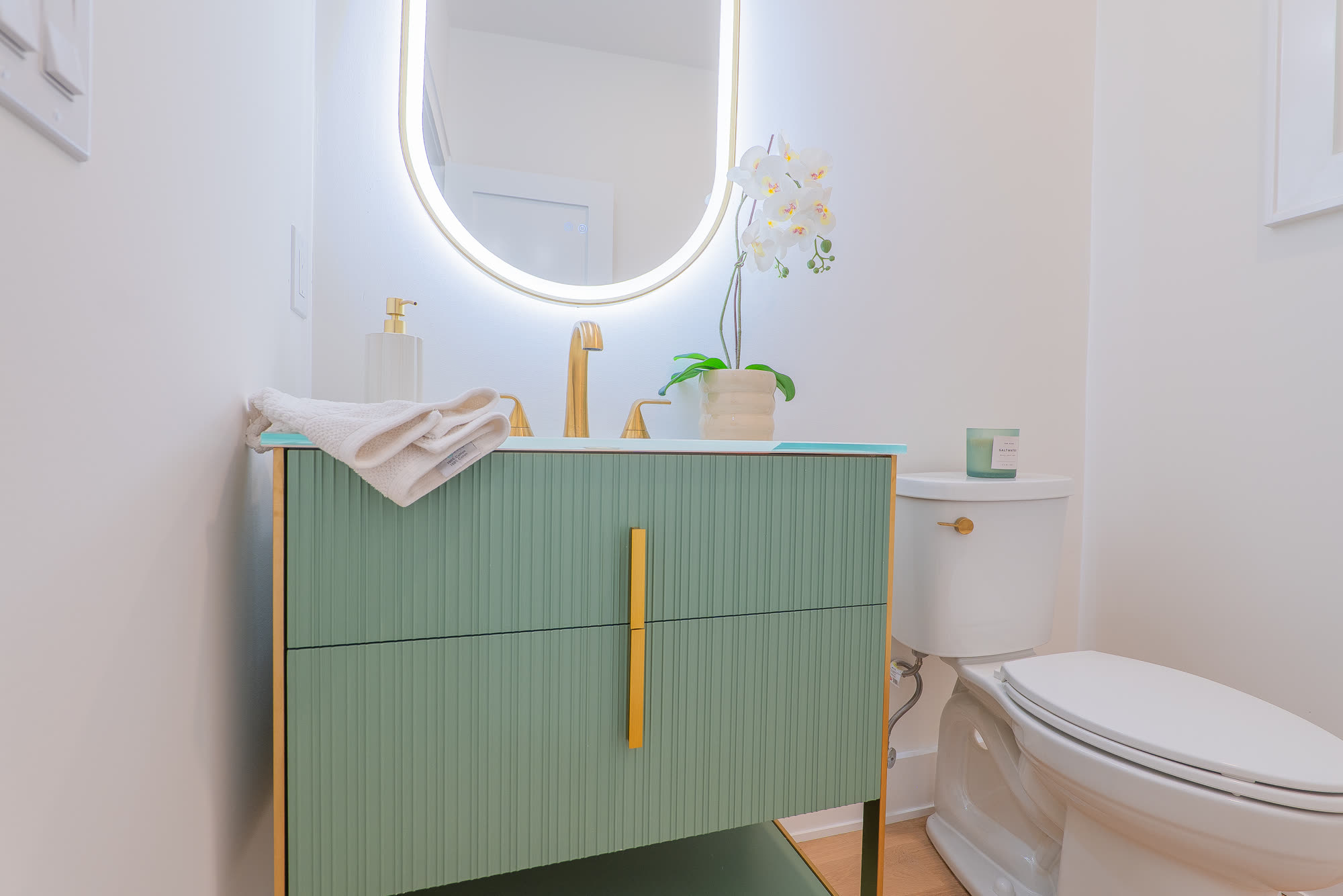Powder room with fluted green vanity and brass fittings